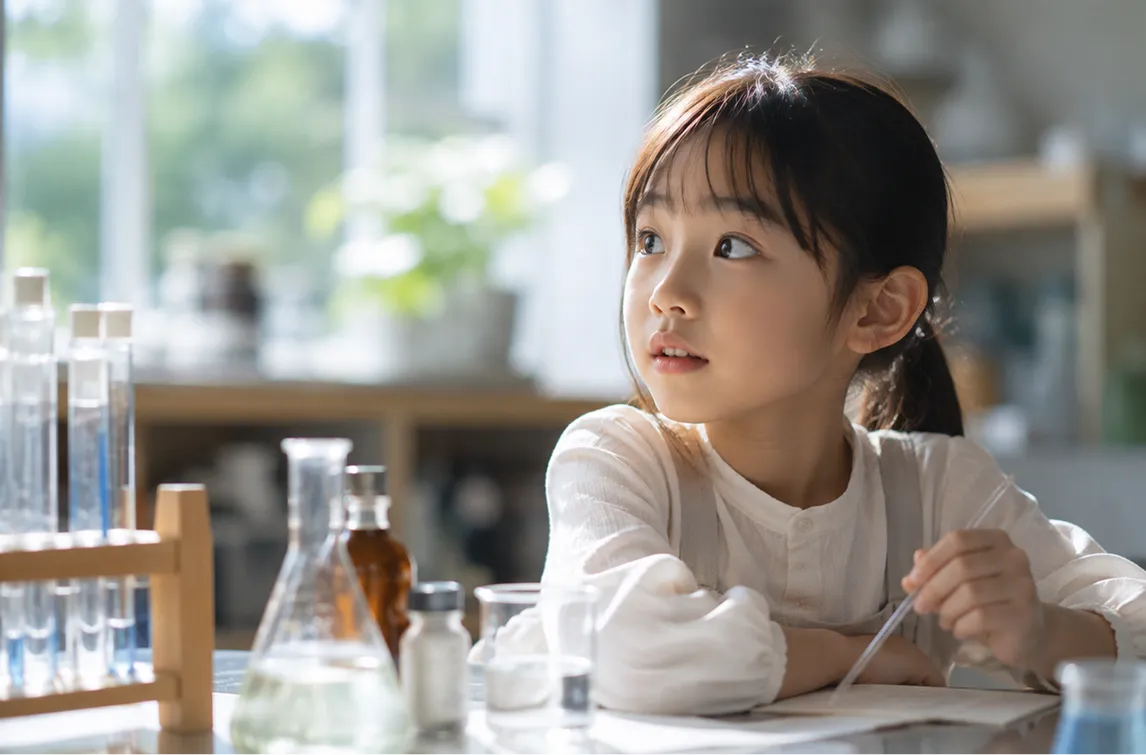 試験管やフラスコを前に科学実験へ取り組む子ども。自分の手で確かめる体験が、化学への「もっと知りたい」を育てていく。