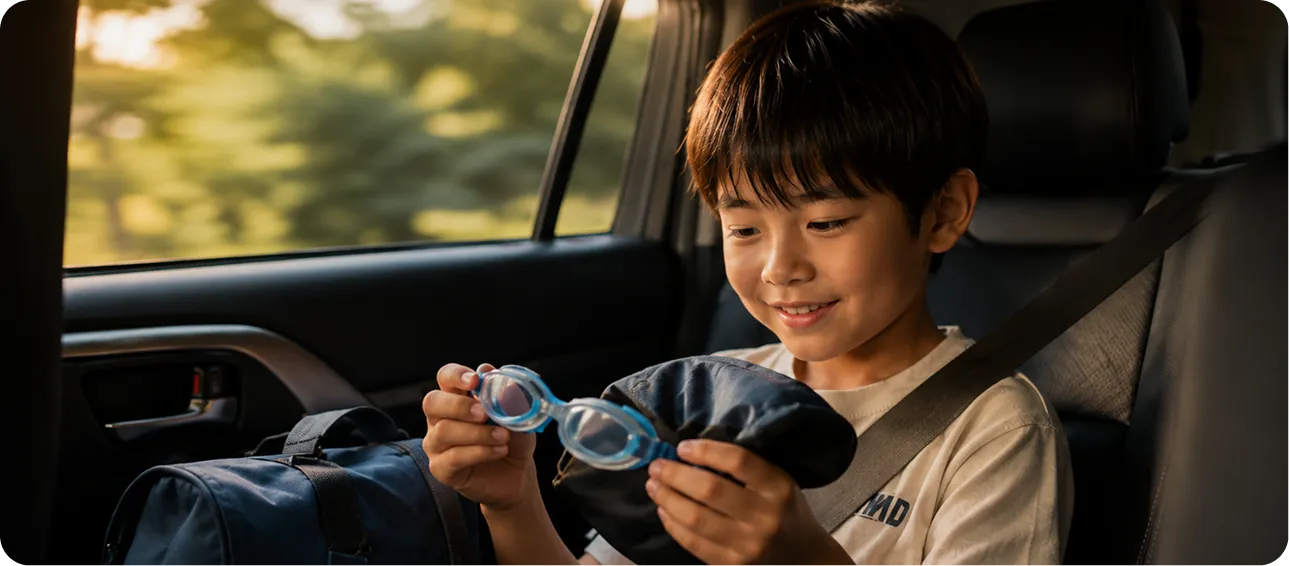 スポーツを終えた帰りの車内でゴーグルを手にする子ども｜Baby-J Sports