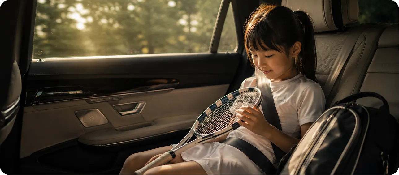 スポーツを終えた帰りの車内でラケットを見つめる子ども｜Baby-J Sports